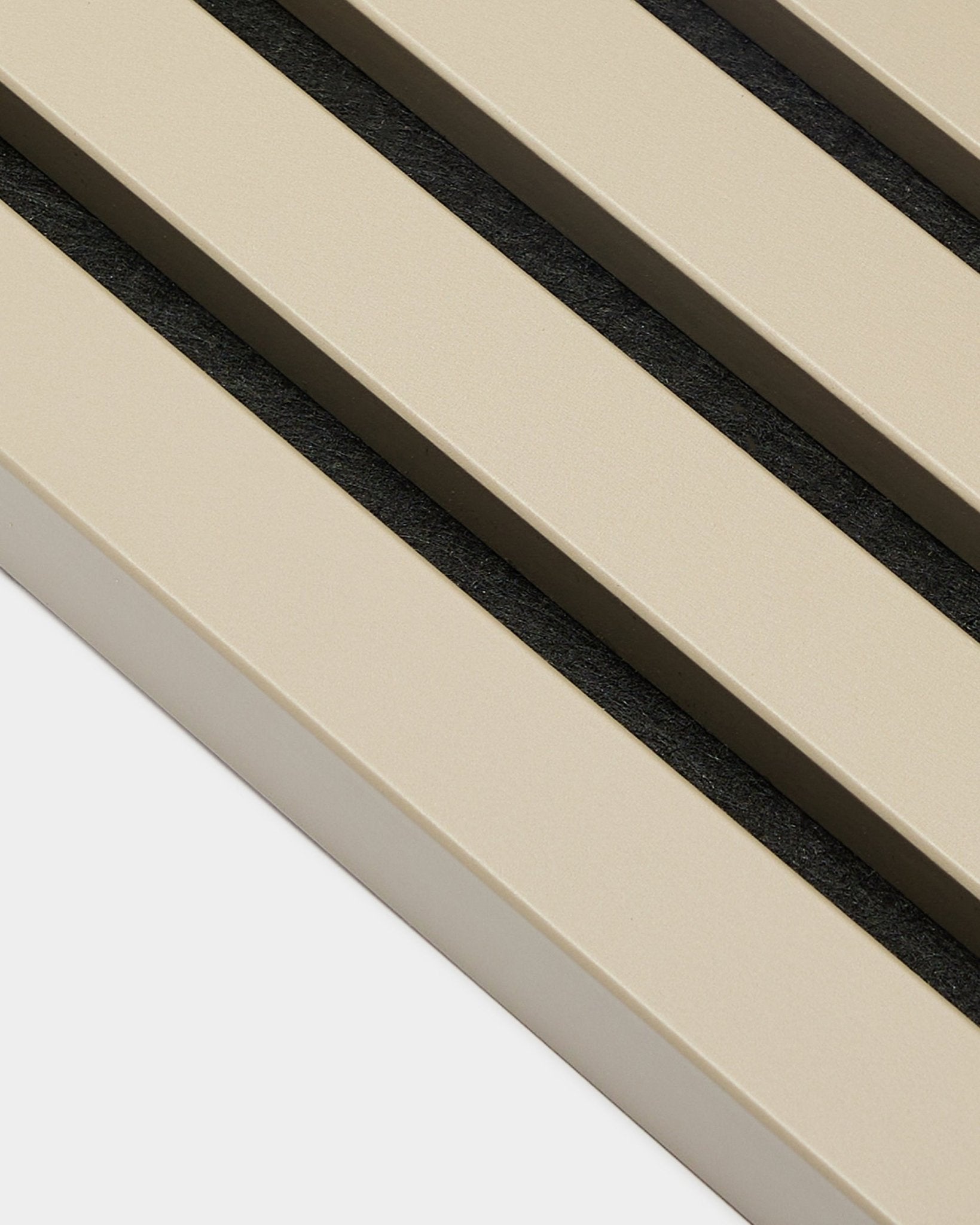 Gros plan sur la lamelle de finition WoodUpp Akupanel en Stone, 2,2 cm — lattes acoustiques beige avec espaces black sur support blanc, adaptée aux murs à panneaux avec cadre MDF.