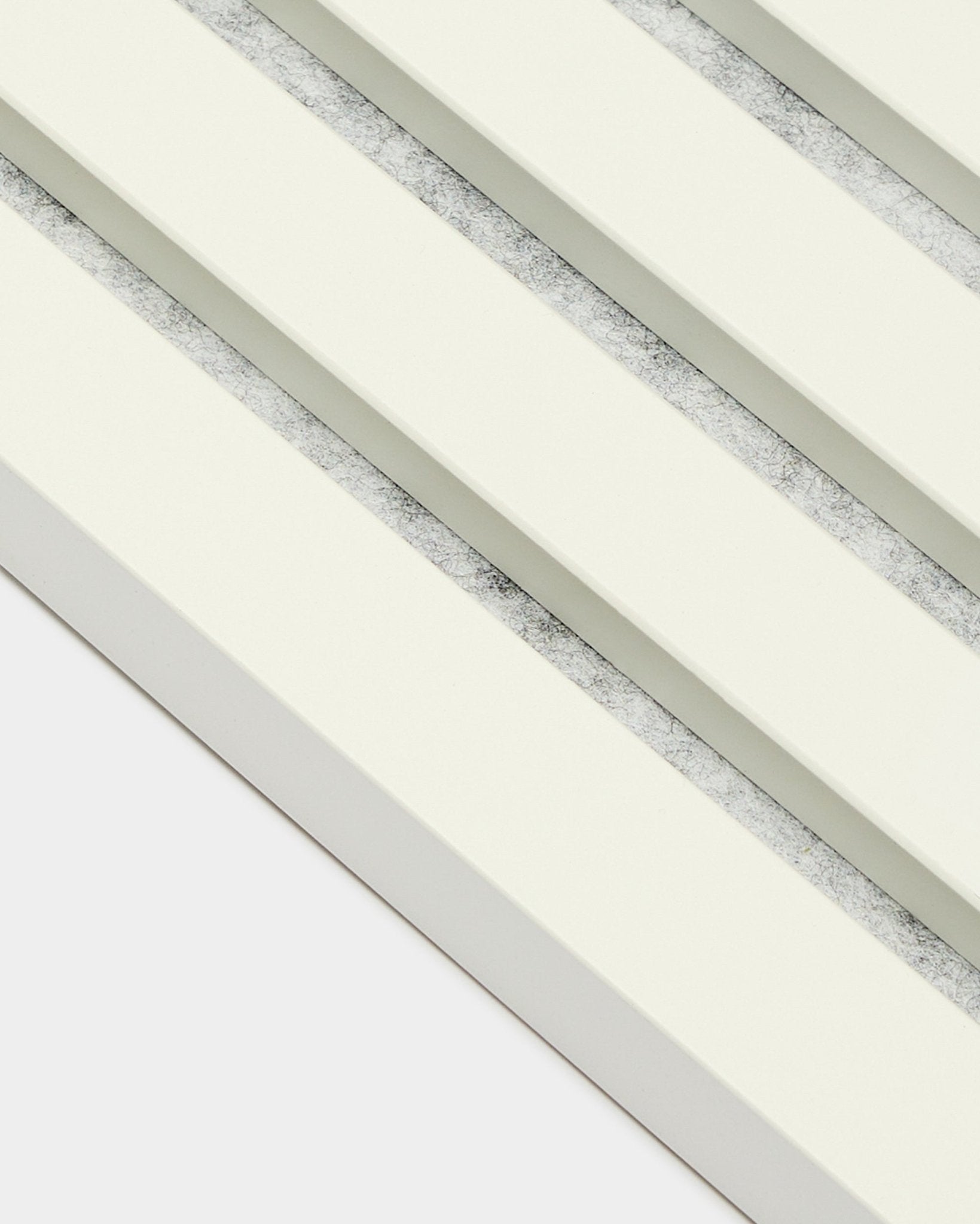 Quatre panneaux acoustiques WoodUpp Akupanel End Lamella/Snow (2,2 cm), disposés en diagonale, avec des lattes blanc cassé et des interstices gris texturés, dans un style nordique.
