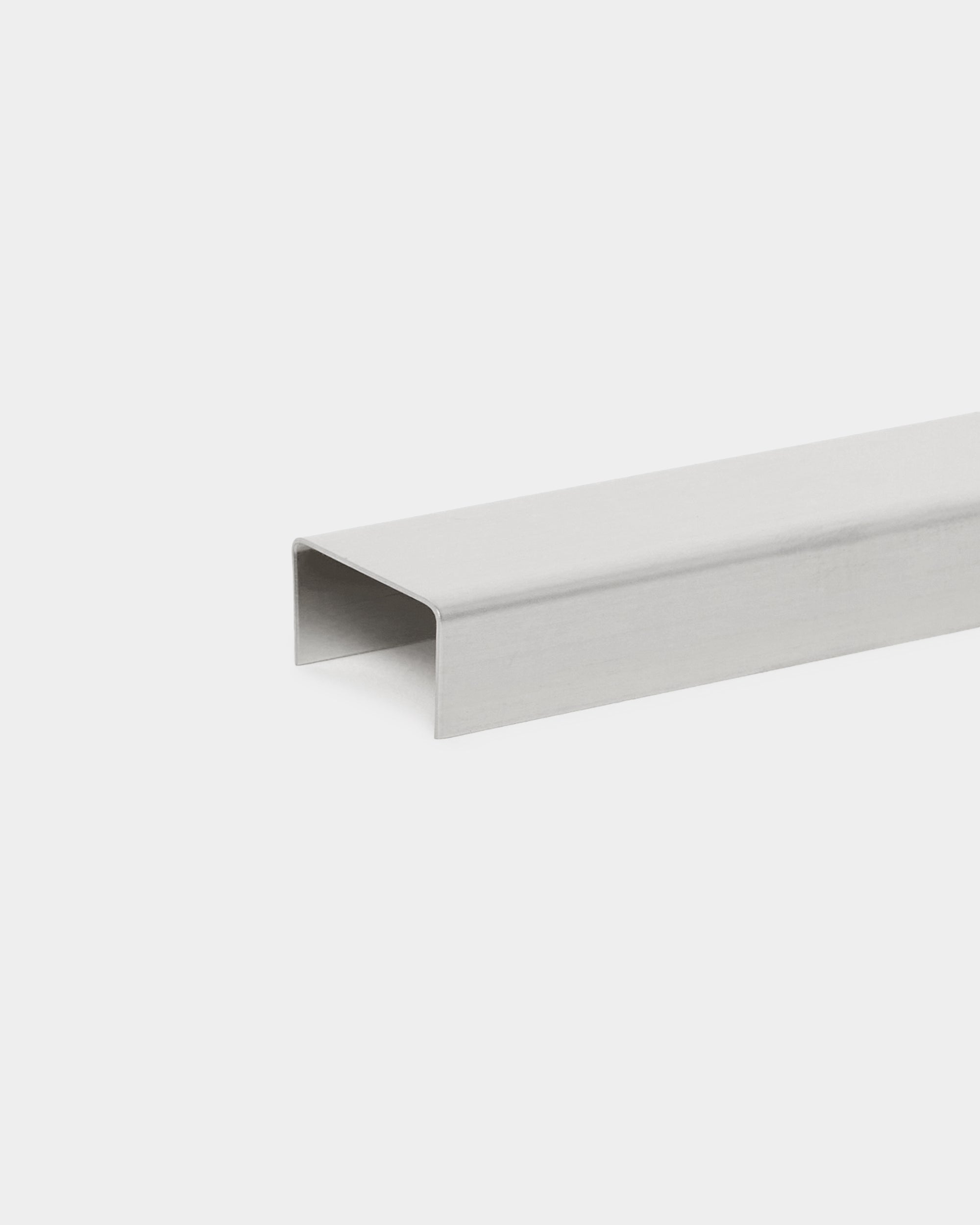 Le Liva Cover par WoodUpp, un accessoire U-channel de 20 cm en steel poli, conçu comme un cache mural minimaliste pour les panneaux acoustiques Akupanel sur fond blanc.