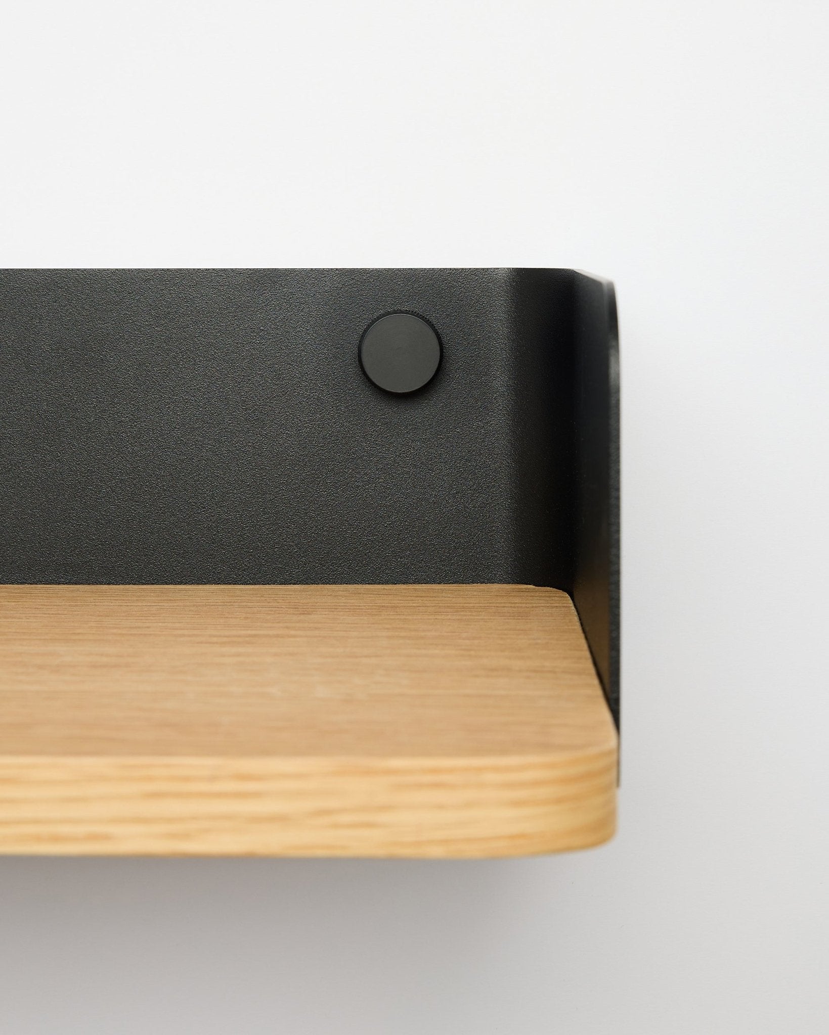 Bibliothèque Linn de WoodUpp en natural oak, largeur 55,9 cm, avec support métallique black, fixée sur un mur blanc ; vue rapprochée depuis le côté droit.