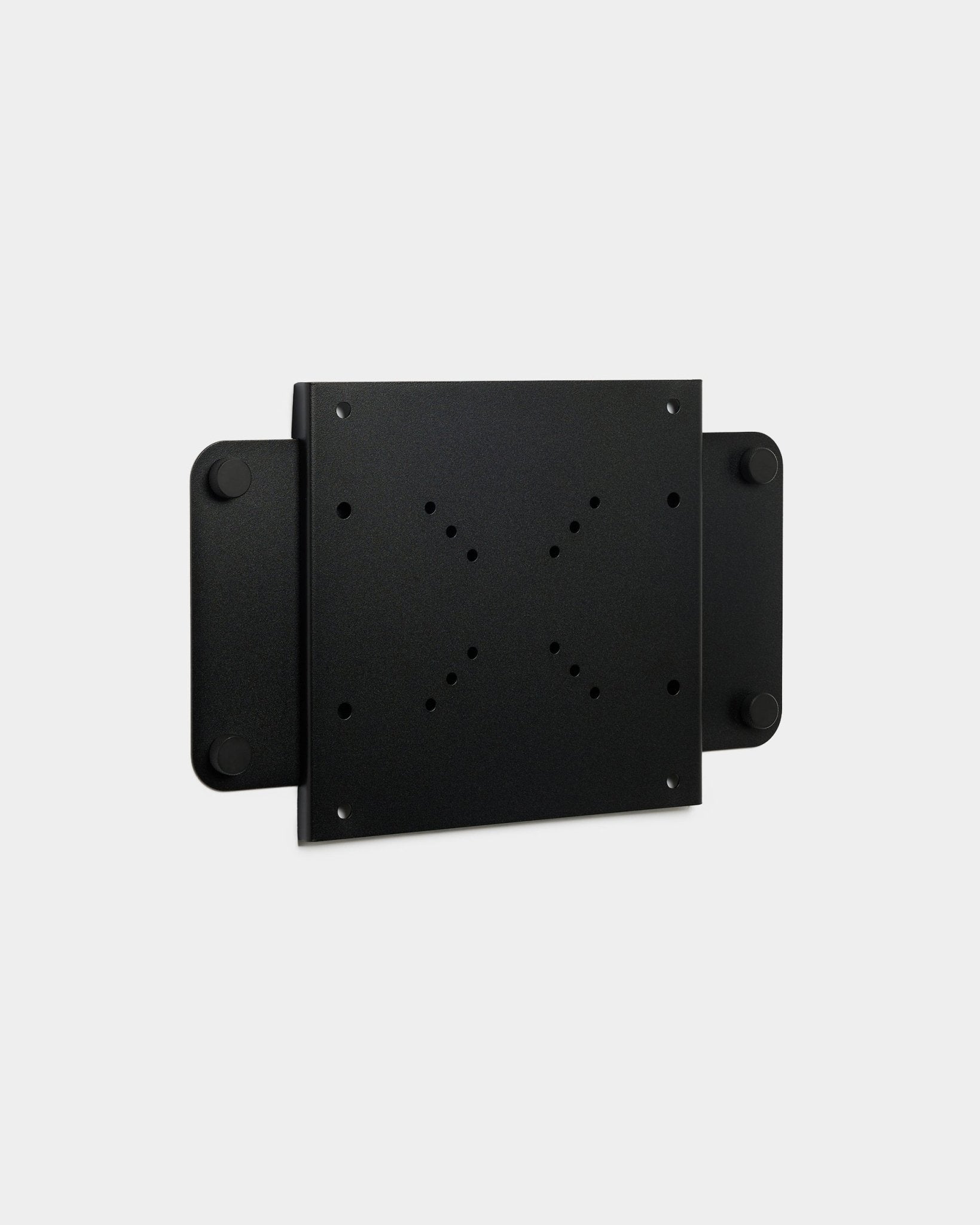 Le Fjell | TV Mount (small) de WoodUpp, un support métallique black avec plusieurs trous de vis et un verrou magnétique, est présenté sur fond blanc.