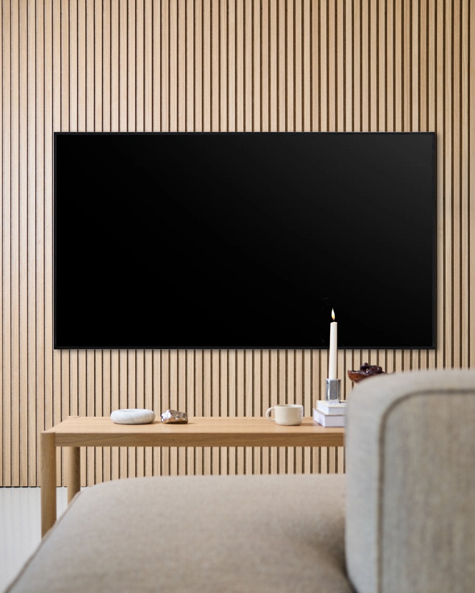 Salon moderne avec téléviseur à écran plat fixé au mur, mur acoustique à lattes en bois Akupanel et table basse en bois pour une ambiance chaleureuse.