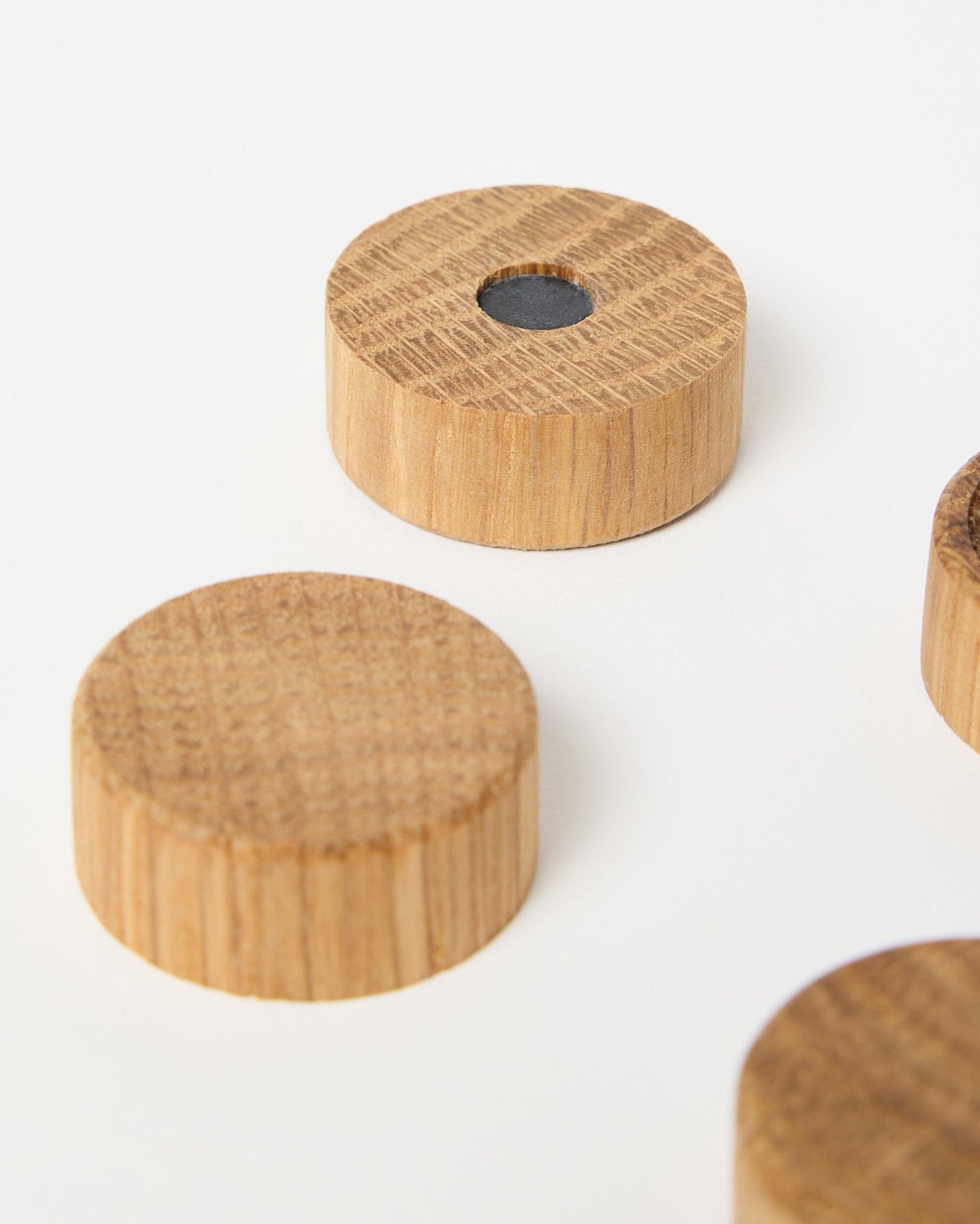 Set de quatre aimants natural oak par WoodUpp, conçus pour être utilisés avec les panneaux acoustiques en bois Akupanel, dont un avec un aimant central en néodyme pour une meilleure tenue, présenté sur fond blanc.