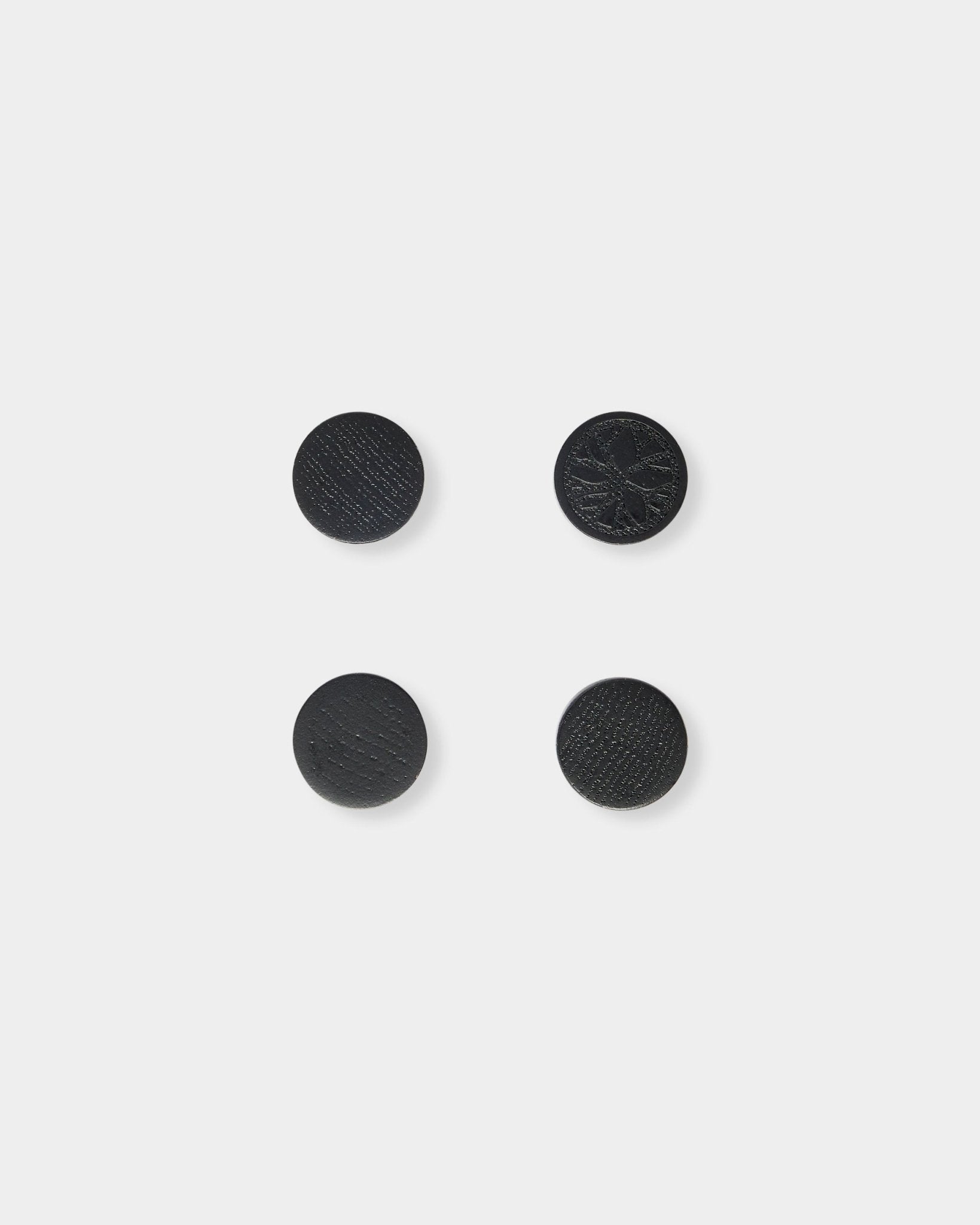 Lot de quatre aimants black oak Norr de WoodUpp, disposés avec soin en carré sur un fond gris clair uni.