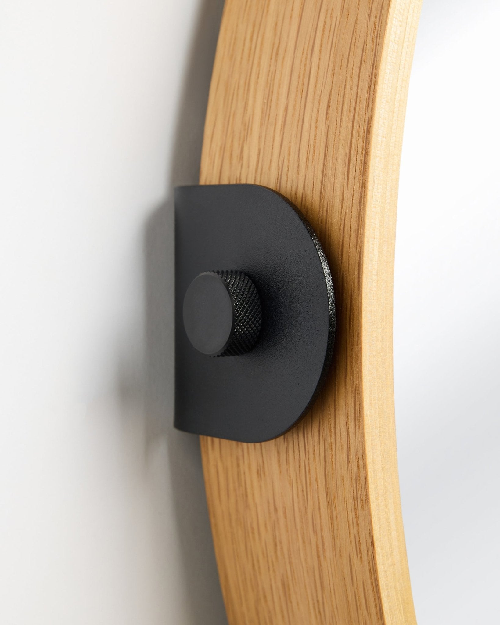 Détail du miroir Linn de WoodUpp en Natural Oak, un Panneau acoustique fixé au mur avec un support métallique black et un bouton rond.
