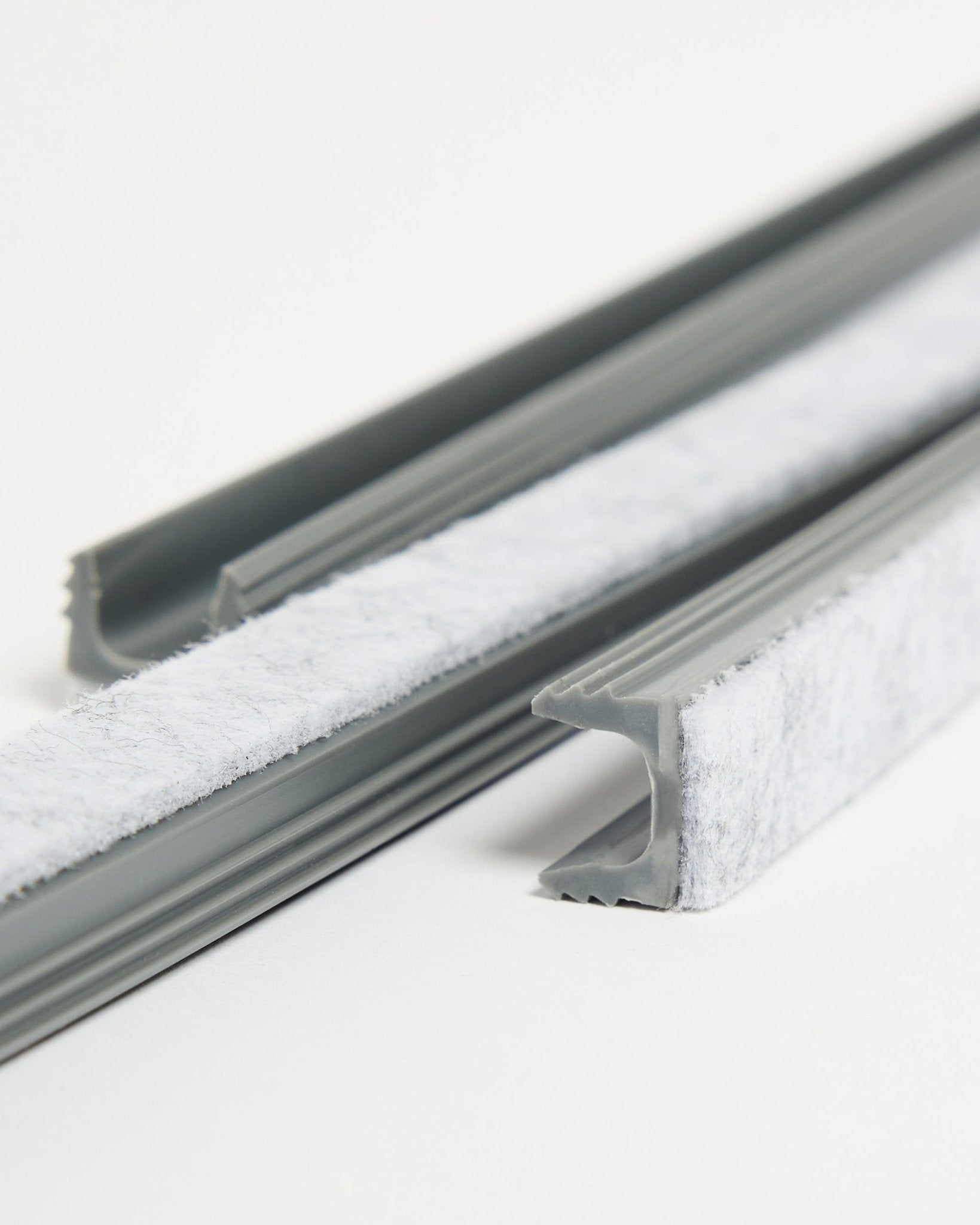 Trois cache-câbles Pop-on WoodUpp Dupps gris, avec joint d’étanchéité blanc et canaux flexibles en TPV, sont posés sur une surface blanche.