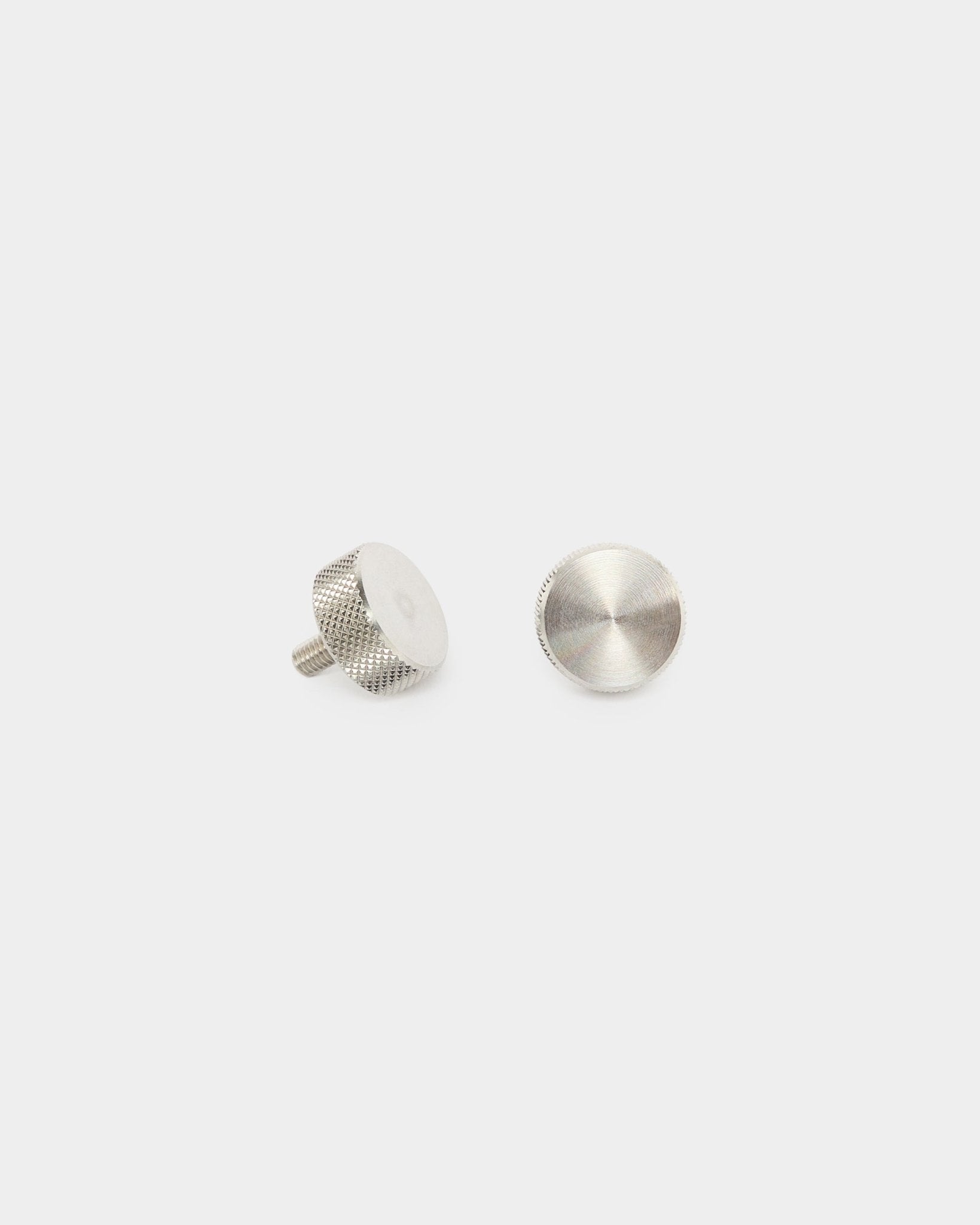 Deux vis moletées WoodUpp en acier inoxydable steel (M5x10 mm, 20x8.8), accessoires pour panneaux acoustiques Akupanel, présentées à la verticale et à plat sur un fond blanc uni.