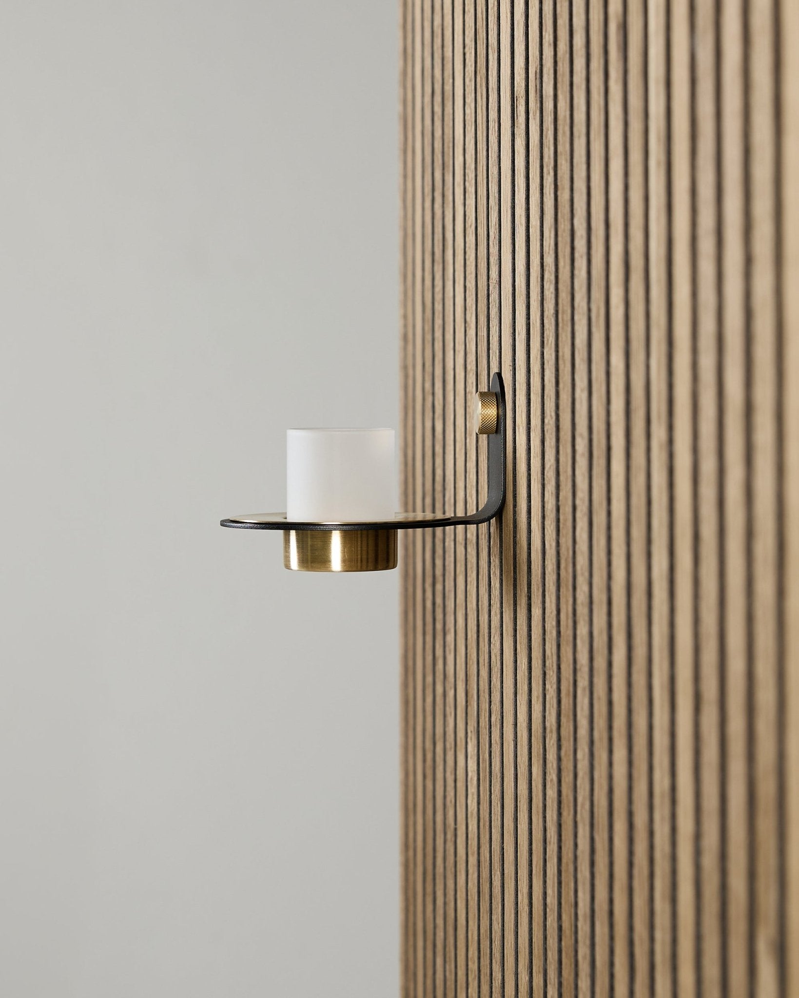 Bougeoir Norr en black et brass de WoodUpp, monté sur un Panneau acoustique Akupanel vertical, avec du verre dépoli et des détails brass.
