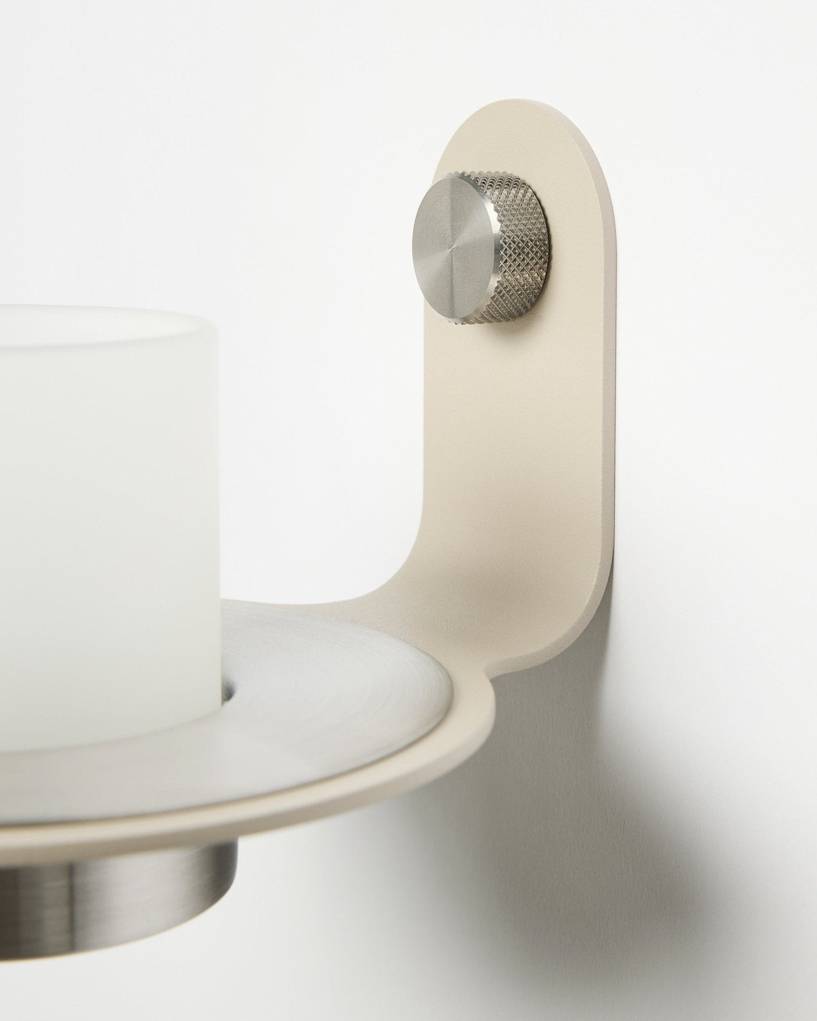 Le bougeoir minimaliste Norr en beige et acier inoxydable steel de WoodUpp, présenté comme accessoire pour les panneaux acoustiques à lattes Akupanel.