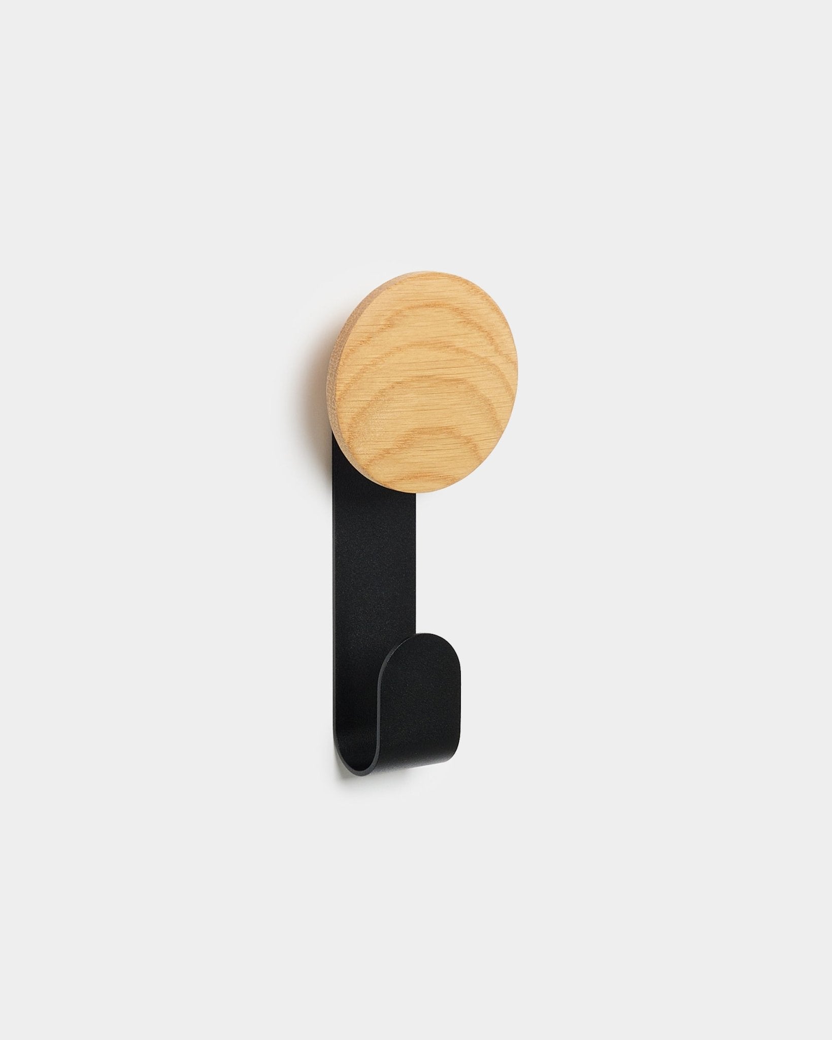 Le porte-manteau Linn Vertical de WoodUpp, avec sa tête ronde en natural oak et son crochet en métal black, est conçu pour suspendre des accessoires sur les panneaux acoustiques en bois Akupanel Nordic.