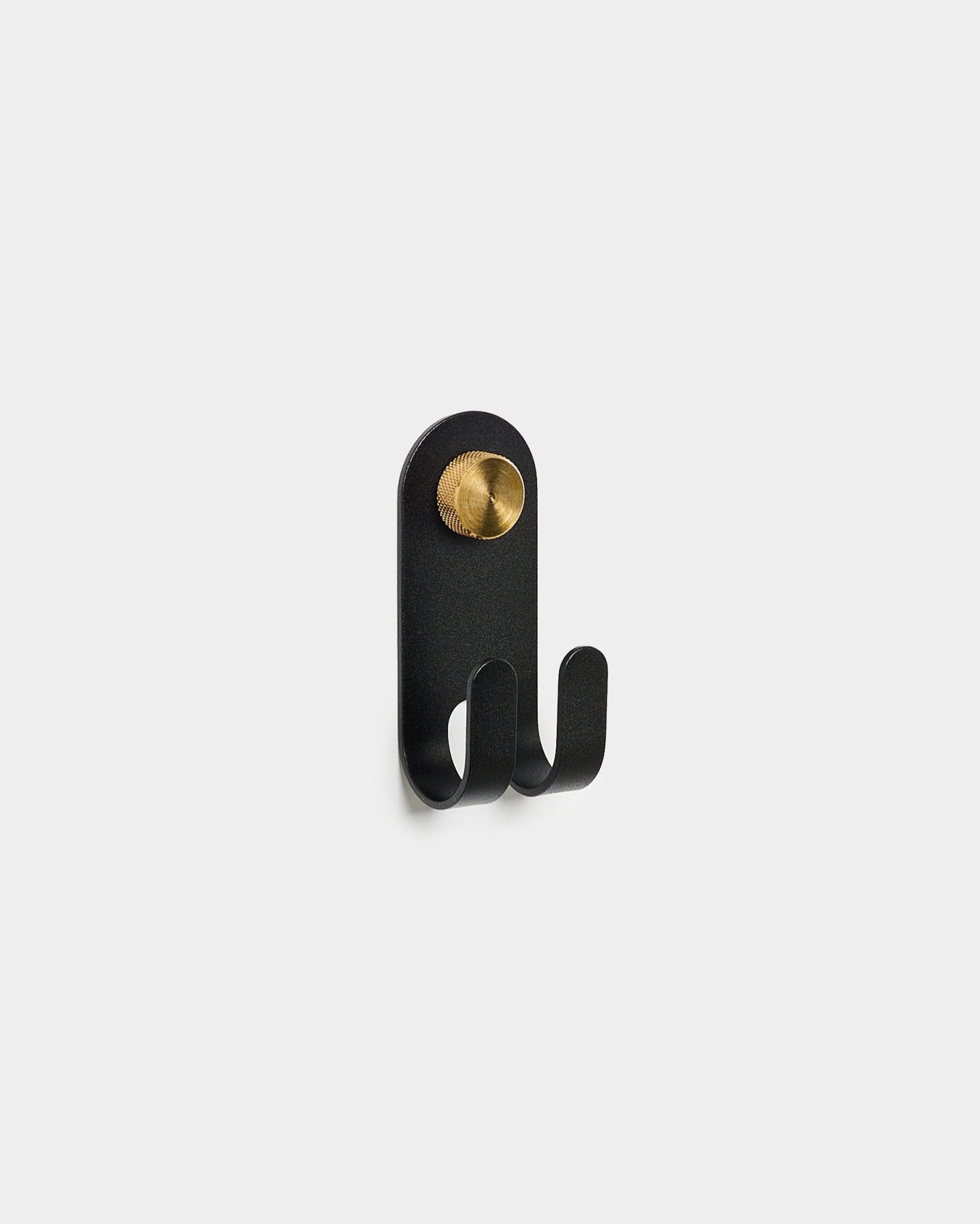 Le Norr Double Hanger de WoodUpp en black, avec deux crochets et un détail rond brass, présenté sur un fond blanc uni.