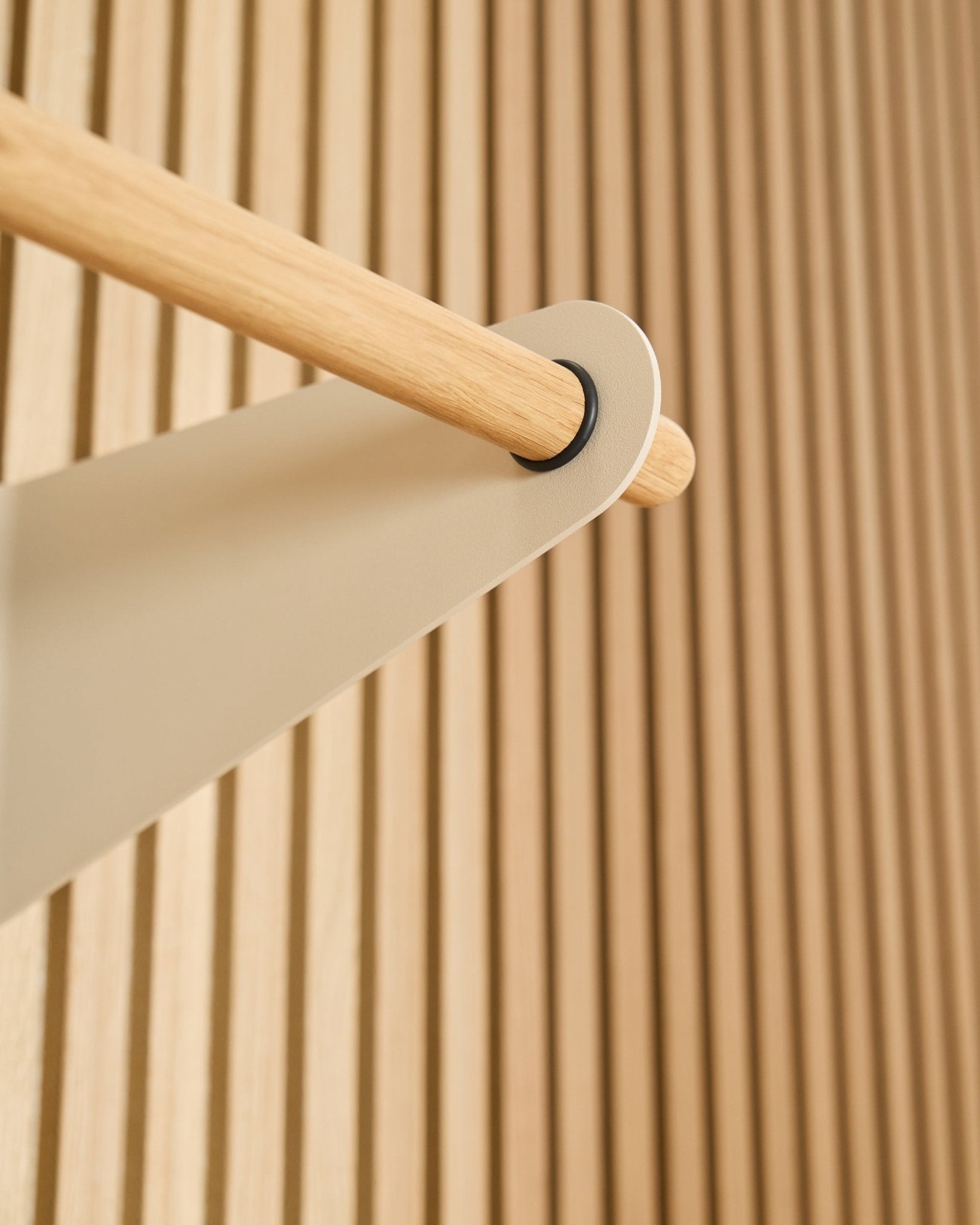 Gros plan sur le portemanteau WoodUpp Linn en beige (75,9 cm), monté sur un support métallique beige, devant un panneau acoustique à lattes texturé Akupanel.