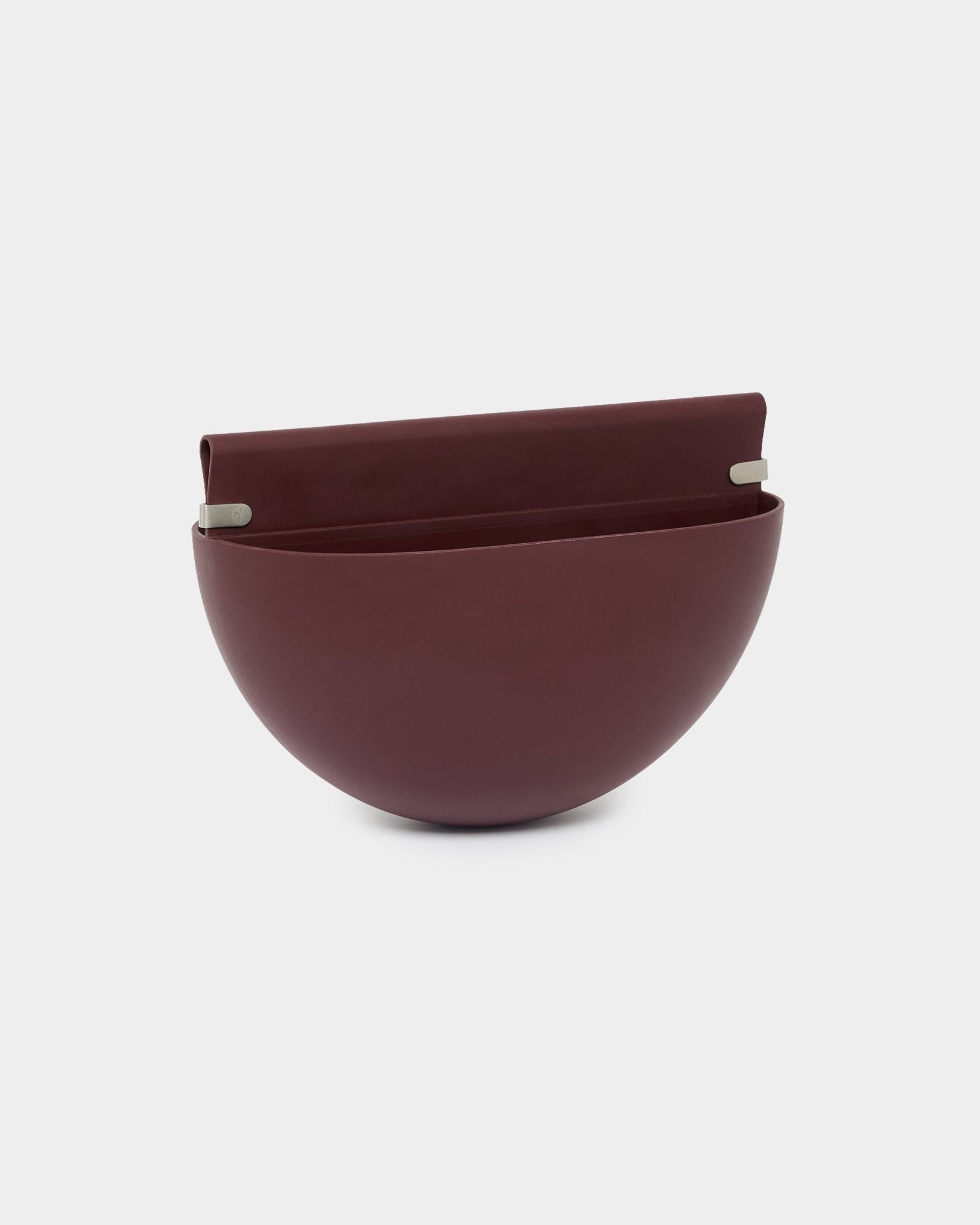 Le cache-pot suspendu WoodUpp Gro Soft Pocket / BM2 en Ox Red, d’une capacité de 4 L, présente une forme en demi-sphère, un dos plat et deux supports métalliques pour le montage sur des panneaux acoustiques.
