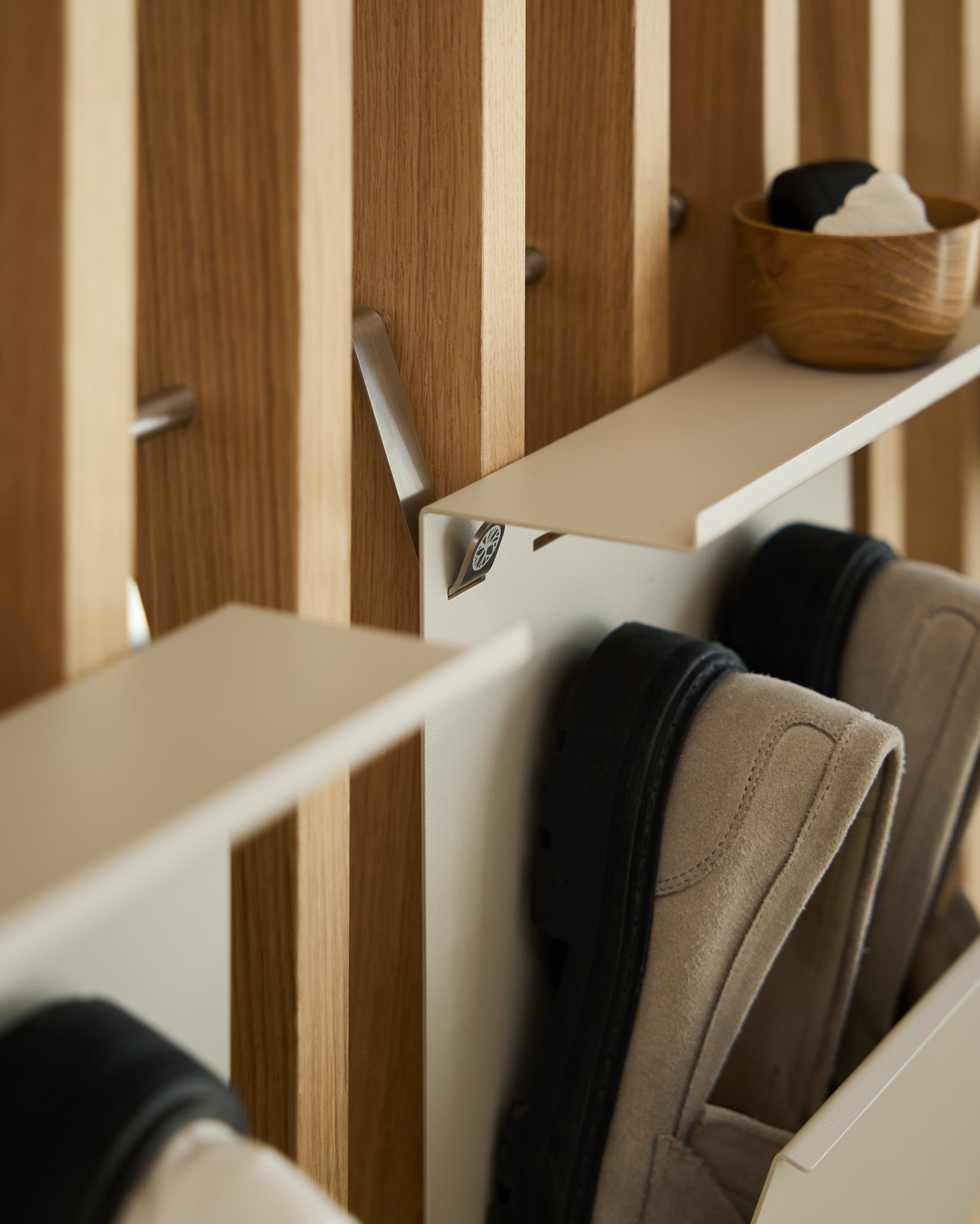 Porte-chaussures minimaliste WoodUpp en beige avec finition thermolaquée steel, monté sur un panneau à lattes nordique Panneau acoustique, avec un bol small pour les clés placé au-dessus.