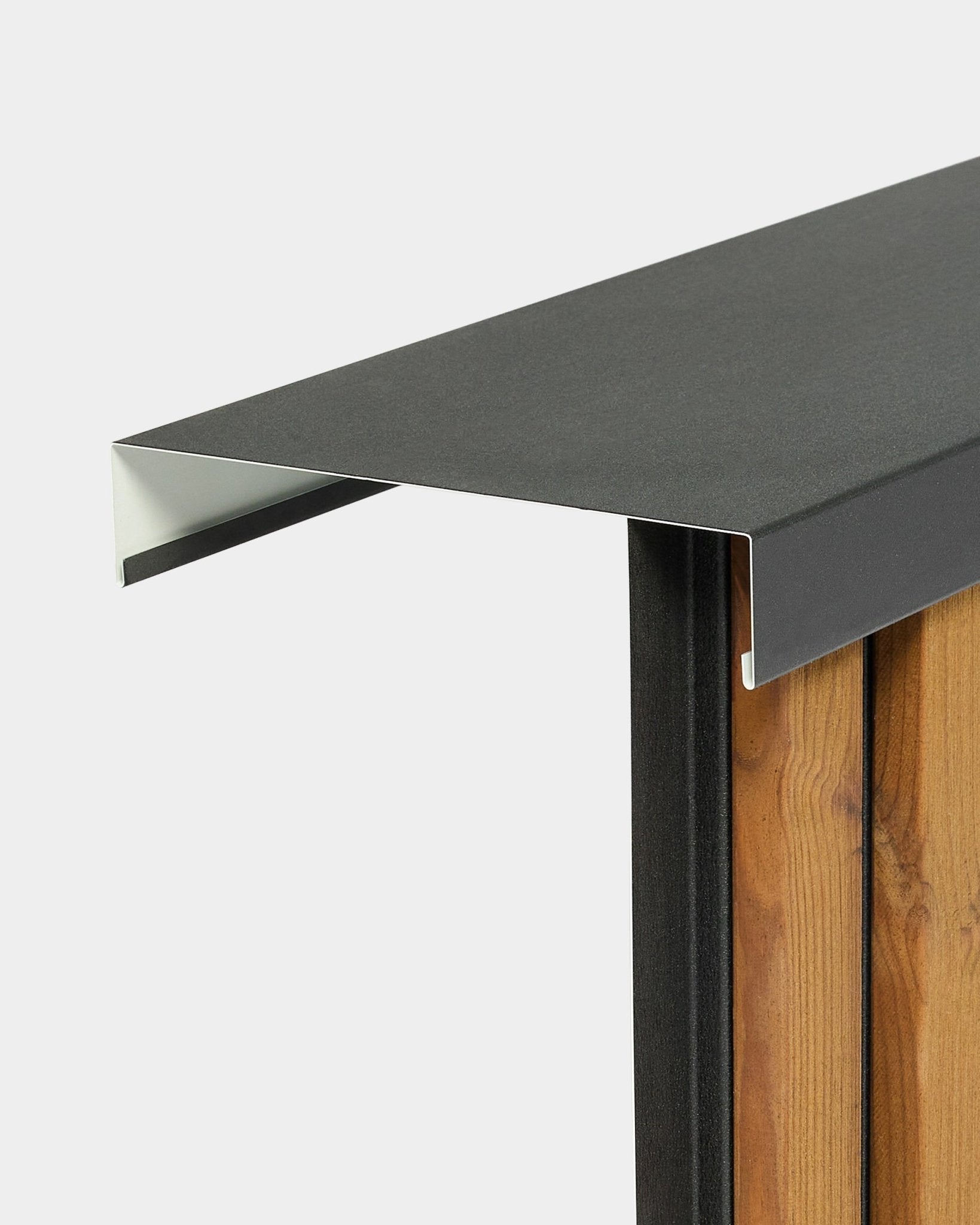 Le couvre-mur WoodUpp Aluwood Level (240 cm x 20 cm) est posé au sommet d’une clôture en bois, avec un profilé en aluminium thermolaqué black qui se prolonge vers l’extérieur.