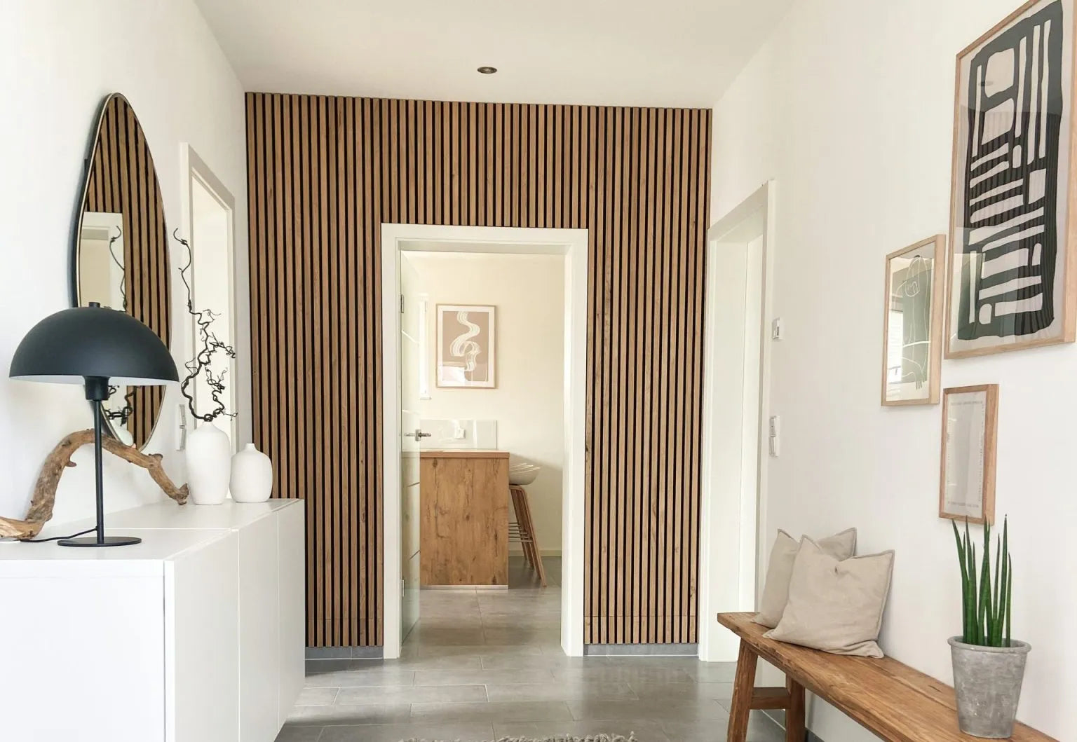 Un couloir moderne avec un mur daccent acoustique en lattes de bois nordique Akupanel, des murs blancs, un banc rembourré et une décoration minimaliste.