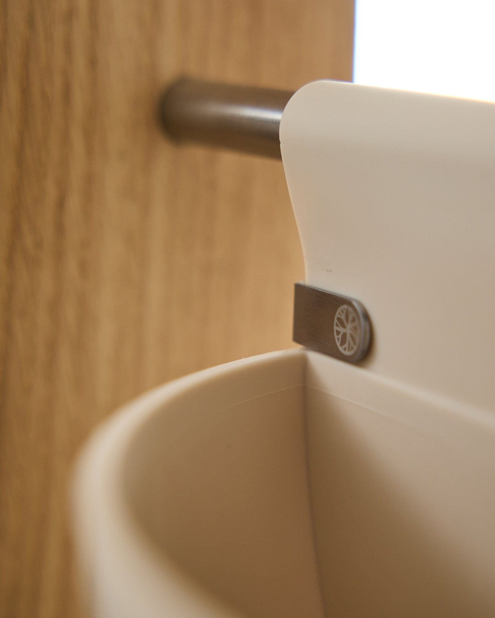 Gros plan sur Gro | Soft Pocket / BM2 (4 l) en beige clair de WoodUpp, suspendu à une tige métallique fixée sur du bois ; arrière-plan flou. Accessoire acoustique nordique.