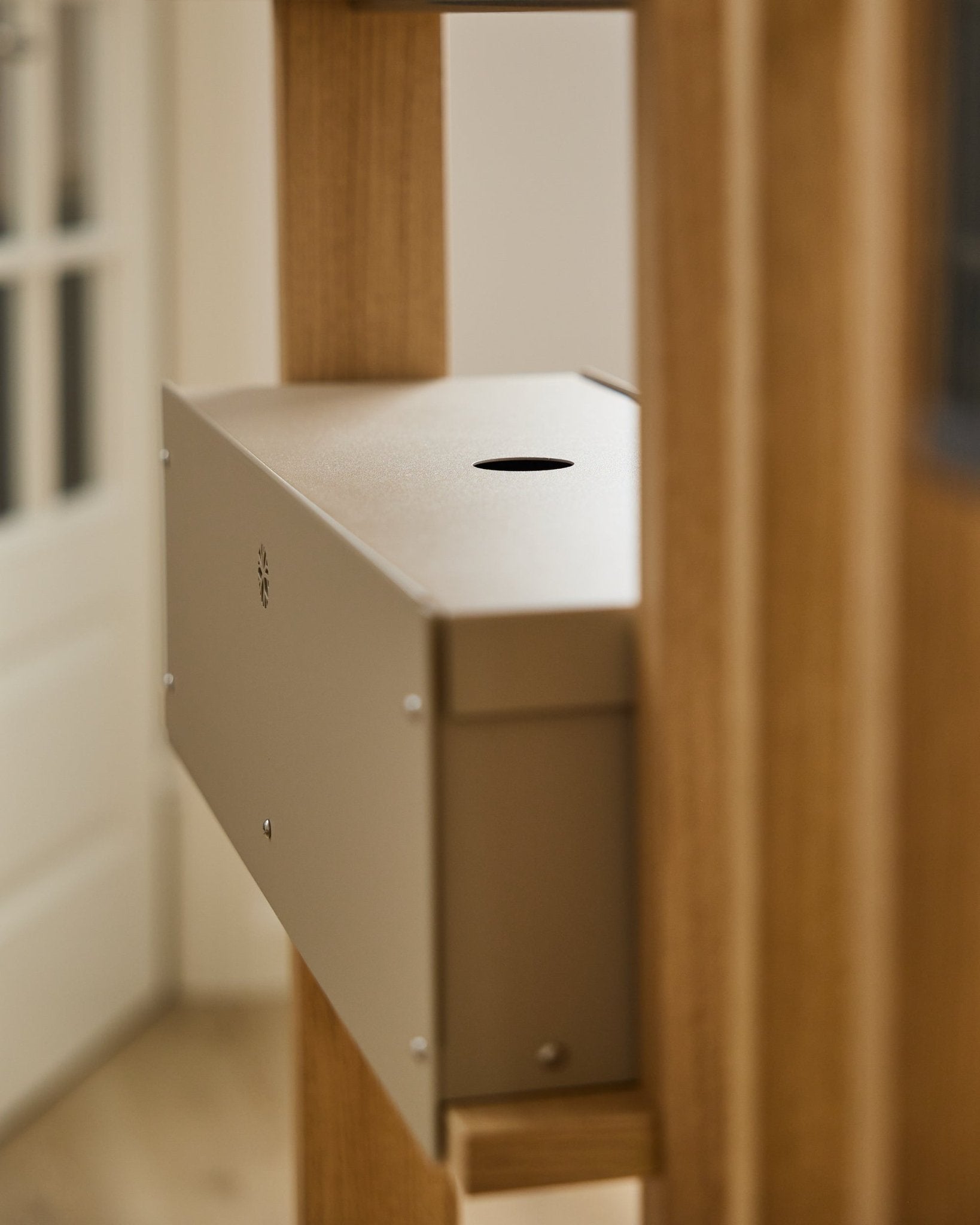 Le Nell | Metal Box / BM2, Beige de WoodUpp est un accessoire en steel thermolaqué de la collection CREATE, installé entre des panneaux acoustiques en bois près d’une porte blanche.